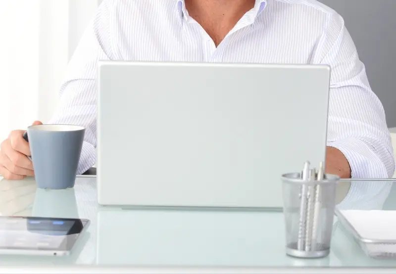 Dental practice manager planning marketing strategy at modern office desk with laptop and coffee