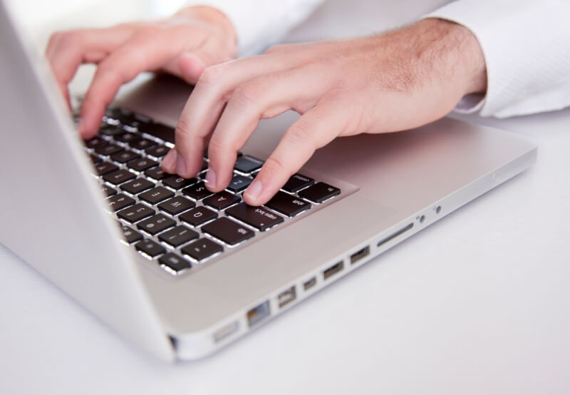 hands on keyboard typing a blog for a dental practice