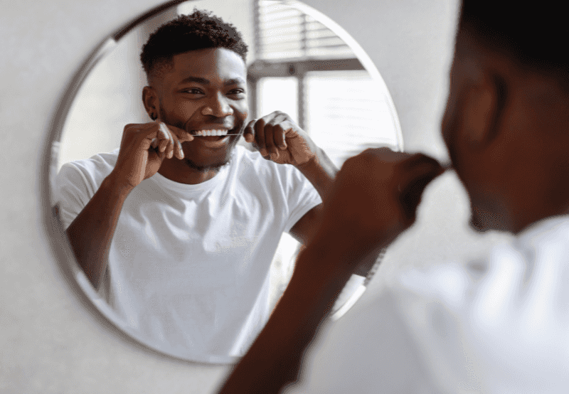 man flossing in mirror